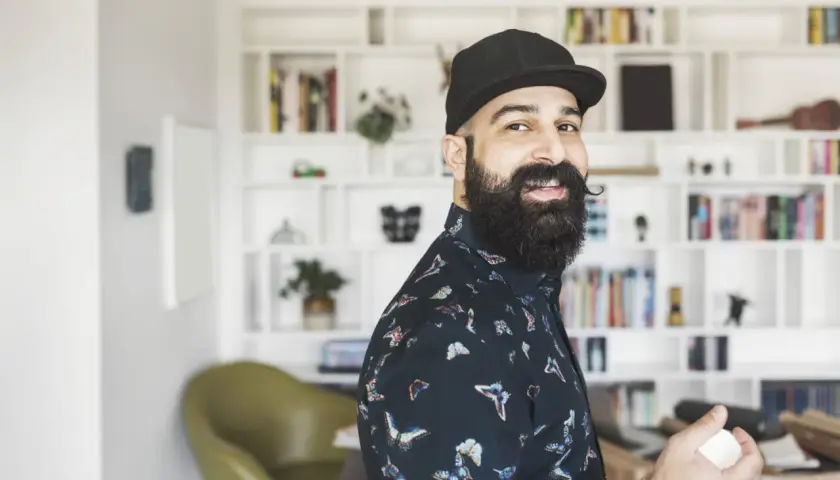 Ein lächelnder Mann mit Bart und Kappe, der als creative director neue Ideen entwickelt.