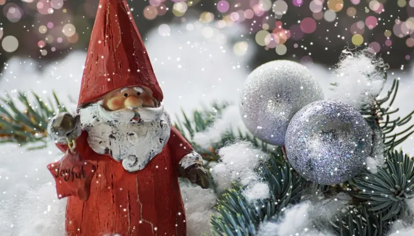 Weihnachtsdeko tipps: Ein Weihnachtsmann mit Stern und Glitzerkugeln auf Tannenzweigen im Schnee.