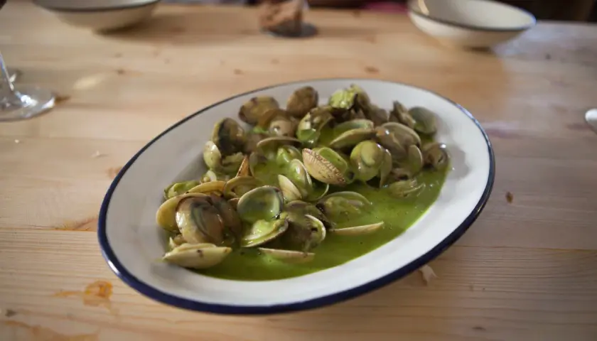 Plato de almejas en salsa verde, un manjar marino bañado en una vibrante y sabrosa salsa.