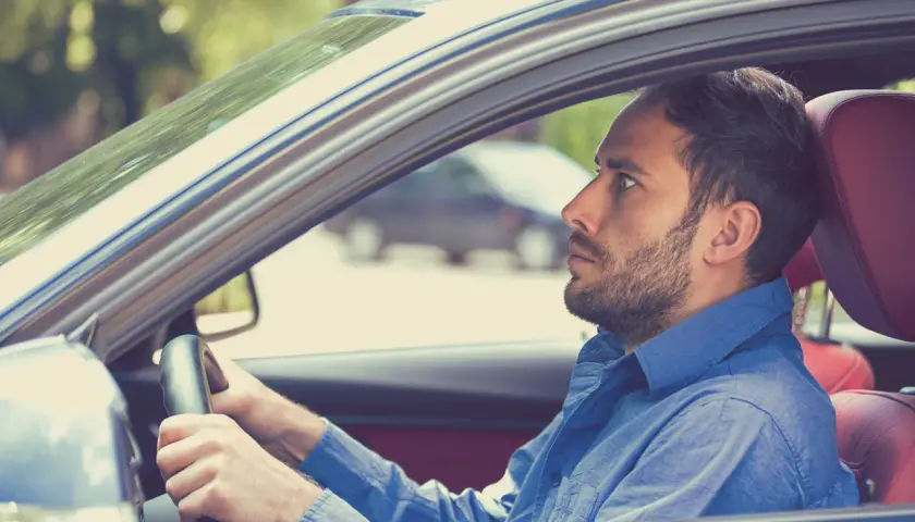 Uomo con espressione tesa al volante, forse a causa della paura di guidare.