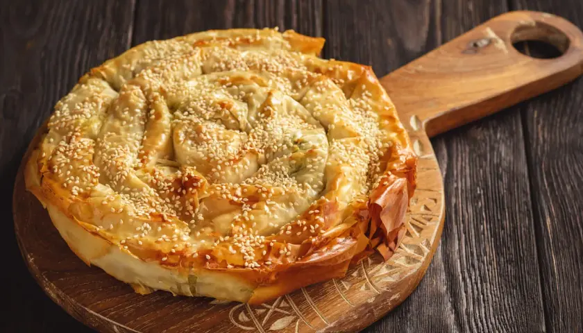 Burek al formaggio, una torta salata a spirale con semi di sesamo, pronta per essere gustata.