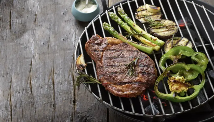 Un steak savoureux, des asperges, des aubergines et des poivrons verts sur un barbecue. Parfait pour savoir que faire cuire au barbecue.