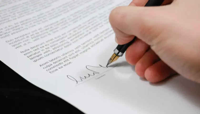 Mano firmando un documento con una pluma estilográfica, un paso clave para firmar contrato online.