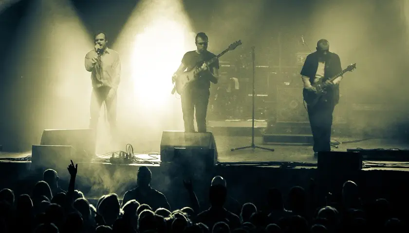 Koncert zespołu Coma z Leszkiem Żukowskim na wokalu. Muzycy na scenie, w tle dym i światła. Publiczność w pierwszym planie.