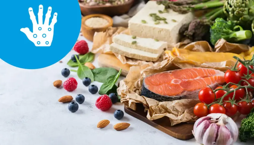 Zdrowa dieta przy łuszczycy: łosoś, warzywa, owoce, orzechy i tofu. Ikona dłoni symbolizuje problemy skórne.