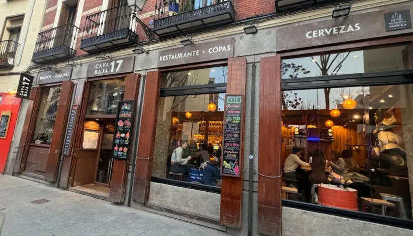 Fachada del restaurante Cava Baja 17, con gente dentro disfrutando de tapas y copas.