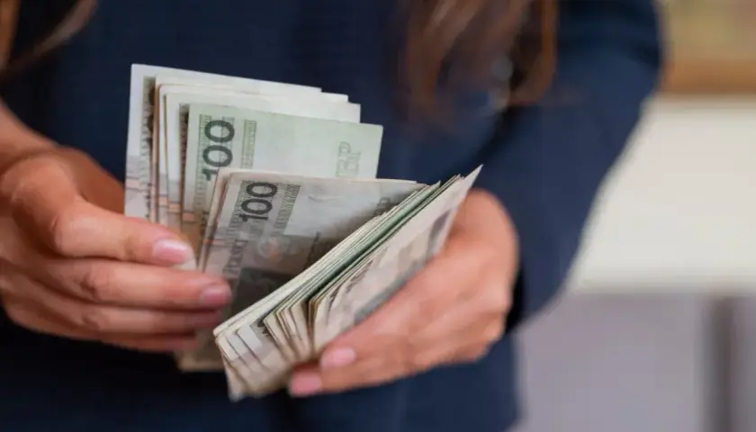 Dłonie trzymające plik banknotów 100 zł. To może być darowizna od rodziców na nowy cel.