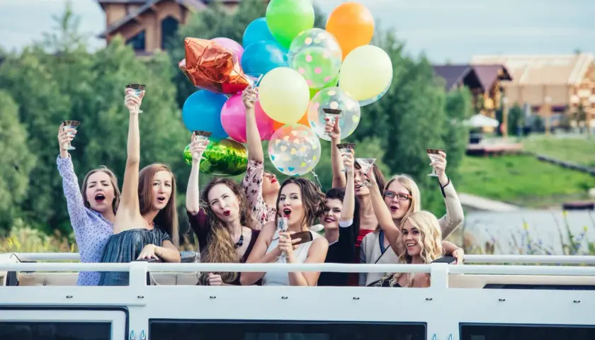 Radosne kobiety z kieliszkami i balonami świętują wieczór panieński.