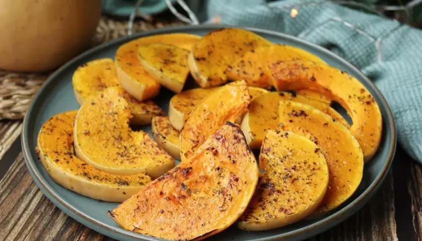 Rodajas de calabaza a la plancha, doradas y sazonadas con hierbas, servidas en un plato azul.