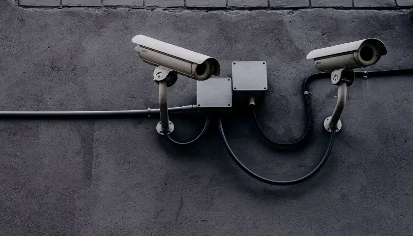 Deux caméras de surveillance fixées sur un mur sombre, évoquant la législation sur la vidéosurveillance et la protection des données.