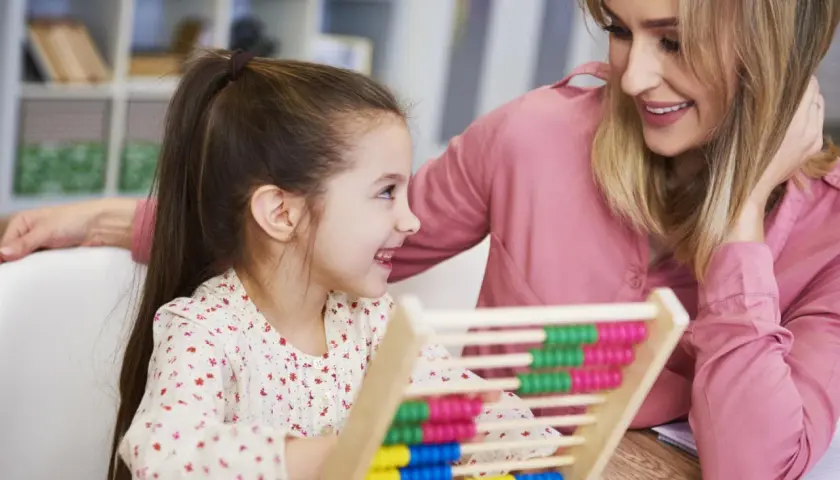 Mutter und Kind üben mit einem Abakus. Ein fröhlicher Moment vor der Einschulung, der den ersten Mathe-Test spielerisch vorbereitet.