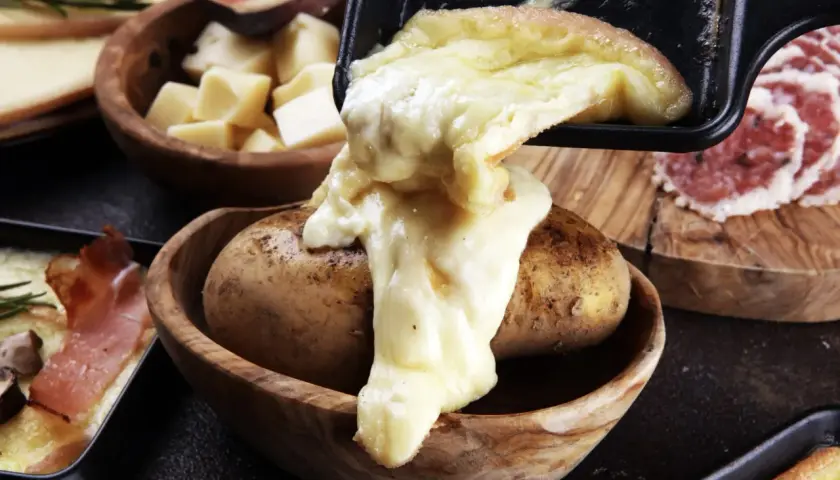 Fromage fondu coulant sur une pomme de terre, signe d'une raclette réussie. Accompagné de charcuterie et de figues.