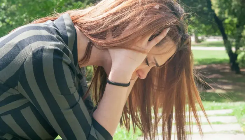 Ragazza con capelli rossi, mani tra i capelli, in cerca di tricotillomania rimedi naturali.