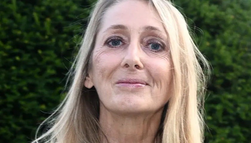 Portret Beaty Pawlikowskiej z blond włosami i niebieskimi oczami na tle zieleni.