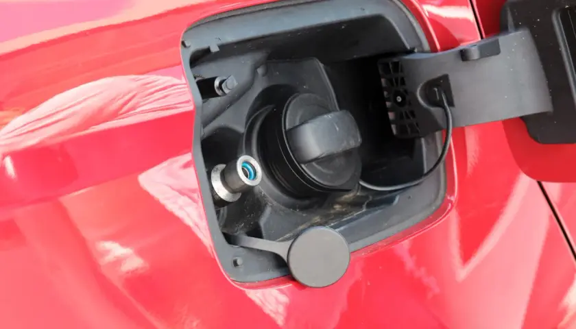 Tapa de combustible de un coche que usa GLP, con boquilla azul y tapón negro.