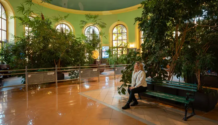 Kobieta odpoczywa w oranżerii, szukając pomysłów na wieczór w Kudowie-Zdroju.
