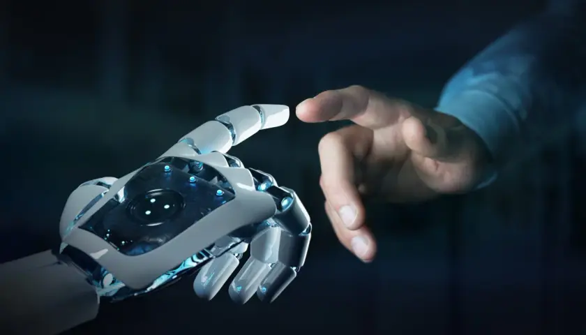 Dotyk ludzkiej dłoni i robota symbolizuje, jak powstała sztuczna inteligencja – połączenie ludzkiej kreatywności i technologii.