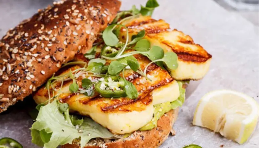 Un délicieux sandwich au halloumi grillé, garni de jalapeños et de jeunes pousses, prêt pour un barbecue estival.