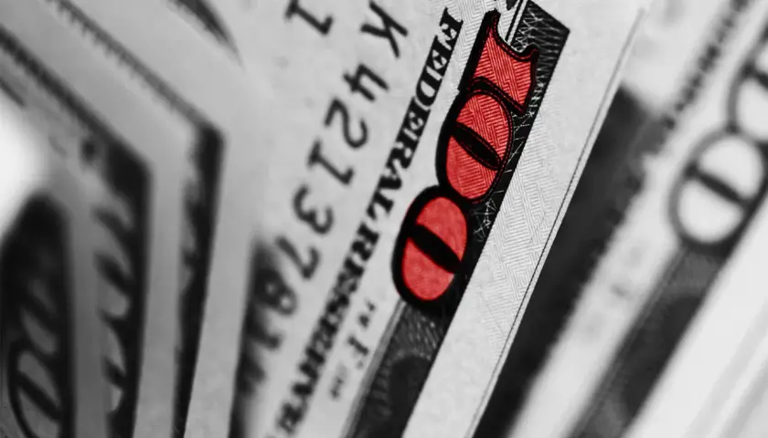 Zbliżenie na banknot 100 dolarów z czerwonym oznaczeniem liczby 100.