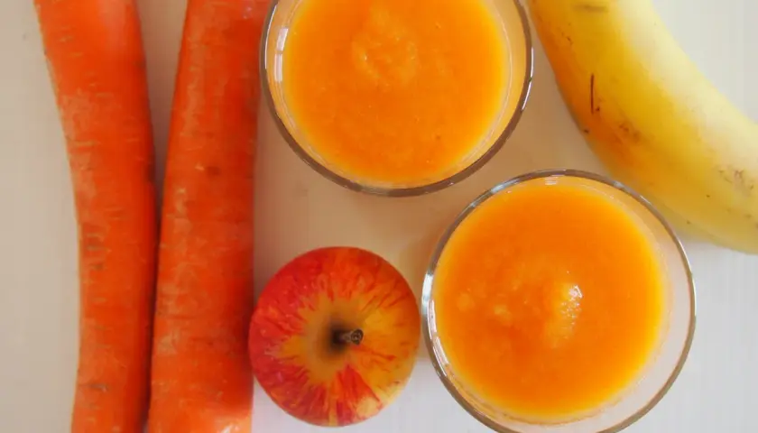 Dwa szklanki domowego kubusia z marchewki, jabłka i banana.