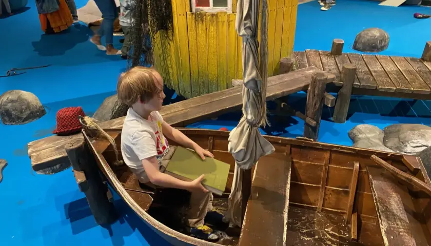Un bambino legge un libro in una barca, un'installazione interattiva che ricorda Stoccolma con bambini.