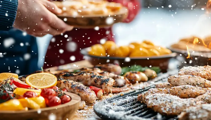 Un **barbecue de Noël** en plein air, avec des saucisses grillées, des légumes colorés et des flocons de neige tombant.