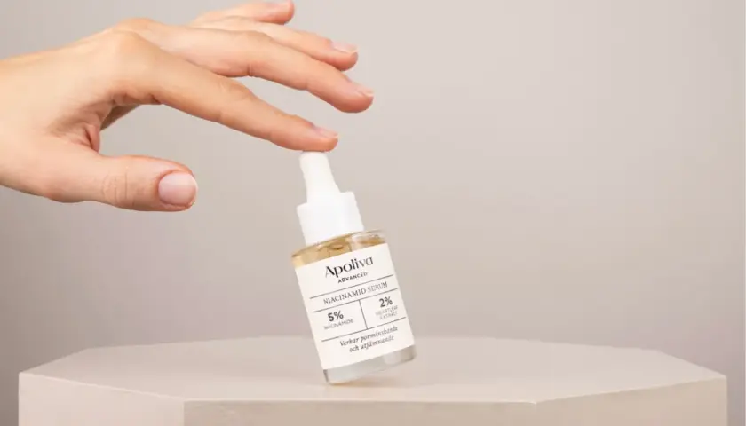 En hand håller en flaska Apoliva Niacinamid Serum, en viktig del av din niacinamide hudvård för en jämnare hy.