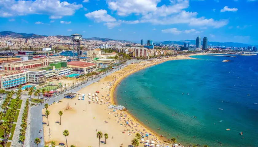 Vista aérea de la playa de la Barceloneta, una de las mejores playas de Barcelona, con gente disfrutando del sol y el mar.