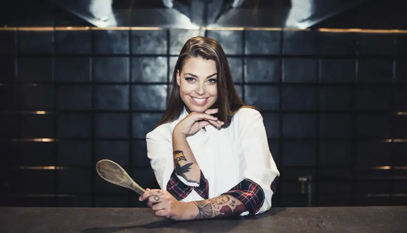 Adriana Marczewska, młoda kucharka z tatuażami, trzyma drewnianą łyżkę.