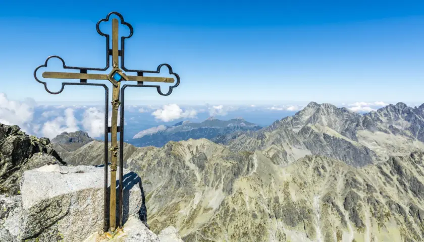 Krzyż na szczycie Gerlach bez przewodnika. Majestatyczne Tatry rozciągają się pod błękitnym niebem.