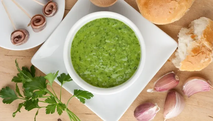 Salsa verde ricetta: prezzemolo fresco, aglio, acciughe arrotolate e pane croccante, ingredienti per un sapore intenso.