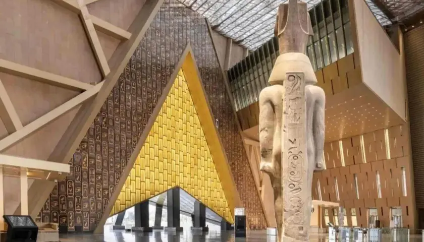 Wielki posąg faraona w nowoczesnym wnętrzu nowego muzeum w Egipcie. Ściany zdobią hieroglify i złote panele.