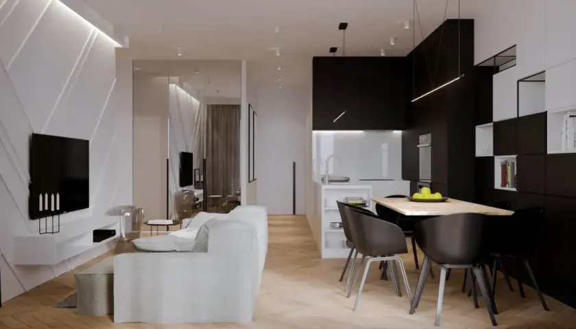 Nowoczesny salon z kuchnią. W salonie biała kanapa, czarny telewizor na ozdobnej ścianie. W kuchni czarne szafki, wyspa, stół z krzesłami. Taśma LED nad kanapą świeci najmocniej.