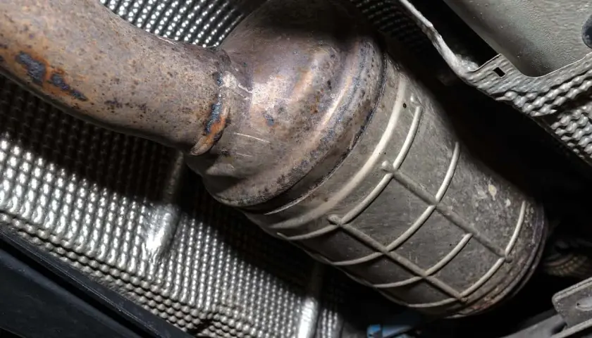 Element układu wydechowego samochodu, prawdopodobnie katalizator lub DPF. Widoczne ślady rdzy i zużycia.