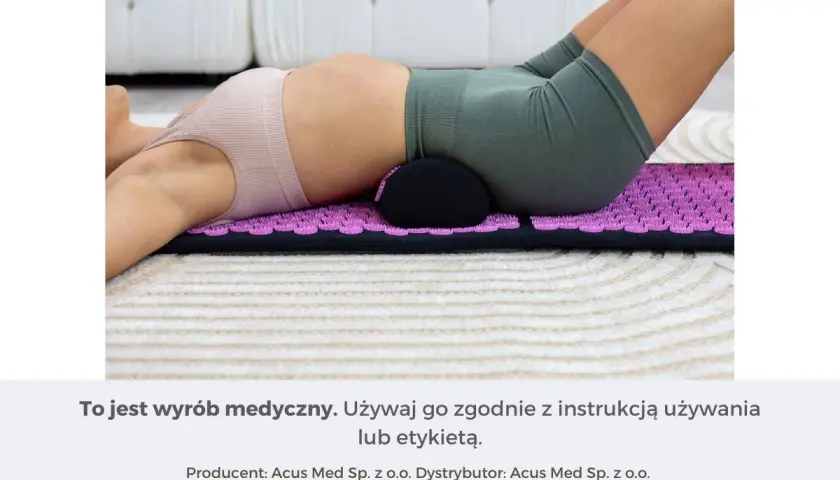 Osoba z bólem kręgosłupa lędźwiowego leży na macie akupresurowej z wałkiem pod odcinkiem lędźwiowym.