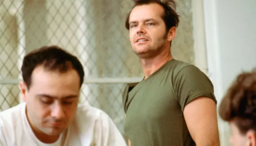 Jack Nicholson, con sguardo intenso, incarna la ribellione nel film "Qualcuno volò sul nido del cuculo", sfidando l'autorità in un contesto di reclusione.