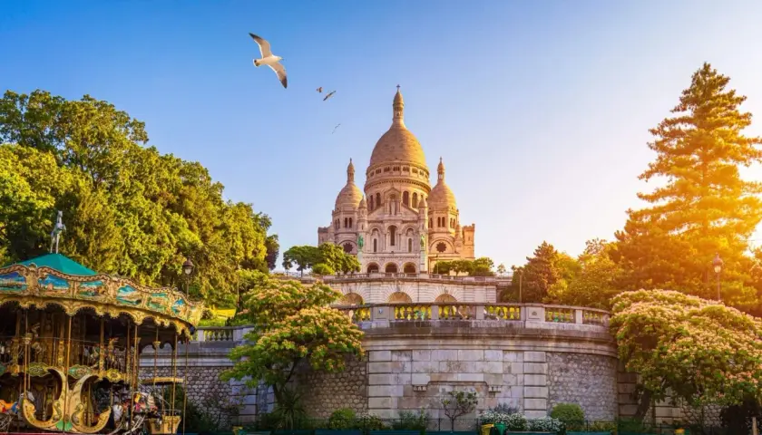 Bazylika Sacré-Cœur na Montmartre, Paryż, z karuzelą i mewą w locie.