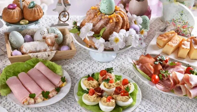 Wielkanocny stół pełen smakołyków: babka, jajka faszerowane, wędliny, ciasto. Idealne inspiracje, co ugotować na święta.