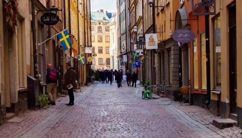 En mysig vandring i Gamla Stan med kullerstensgator, svenska flaggor och historiska byggnader.