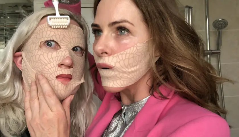 Två kvinnor med ansiktsmasker. En använder en microneedling-roller. Frågan om microneedling hemma hur ofta är relevant för denna typ av behandling.