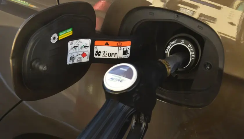 Tankowanie samochodu. Dystrybutor z napisem "diesel" wlewa olej napędowy do baku.