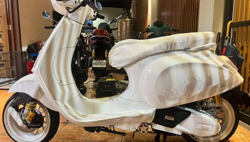 Vespa bianca personalizzata con fiamme, un vero gioiello a 2 tempi pronto a sfrecciare.