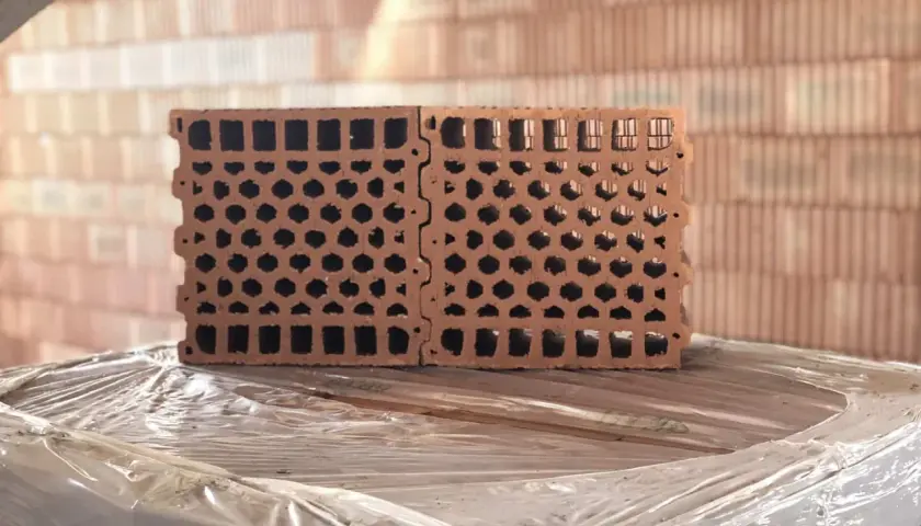 Blocchi forati in laterizio, ideali per l'isolamento acustico, impilati su un bancale.