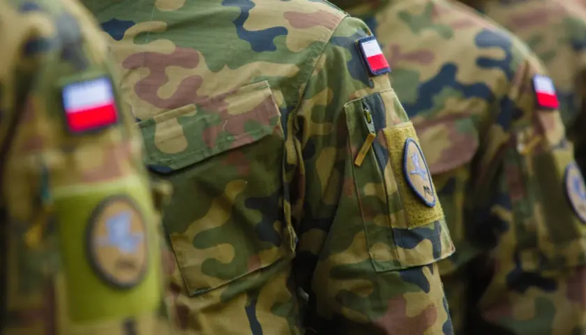 Żołnierz RP w mundurze moro, z naszywką z polską flagą. Dumnie reprezentuje kraj.