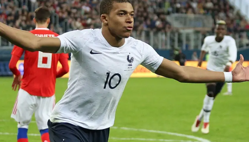 Kylian Mbappé w białej koszulce z numerem 10, świętuje bramkę. Jego waga jest idealna do szybkich sprintów.