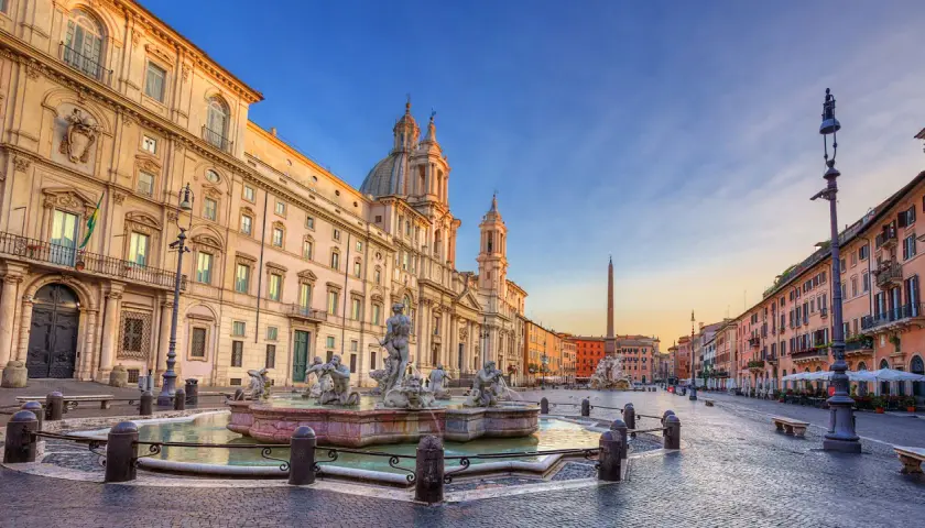 Fontana dei Quattro Fiumi e la chiesa di Sant'Agnese in Agone, simboli della piazza Navona storia, sotto un cielo al tramonto.