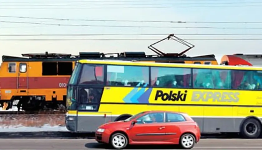 Pociąg i żółty autobus "Polski Express" jadą obok siebie. Czerwony samochód na pierwszym planie. Podróż z Poznania do Lublina?