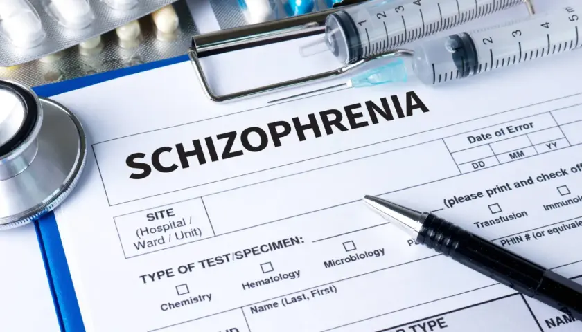 Lekarz wypełnia formularz "Schizofrenia", obok leżą strzykawki, stetoskop i opakowania leków, w tym risperidon.