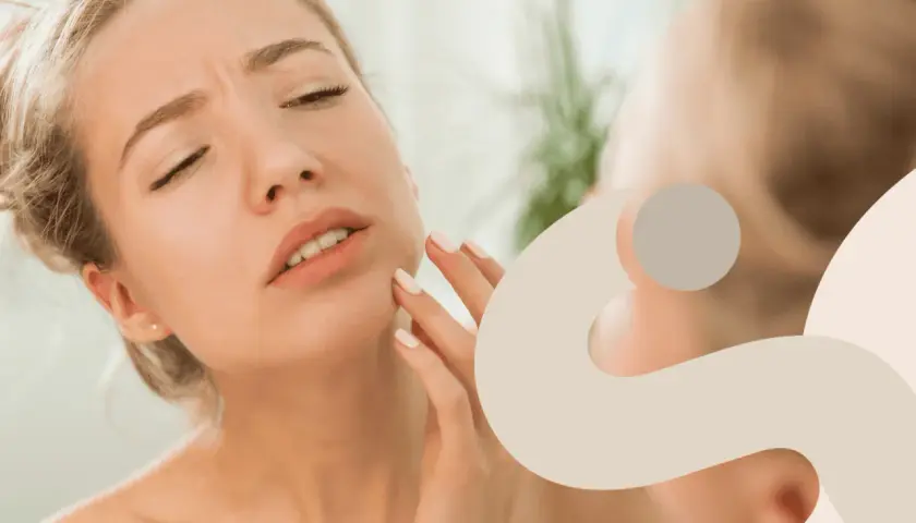 Donna con viso irritato che si tocca la guancia, preoccupata per la sua pelle.
