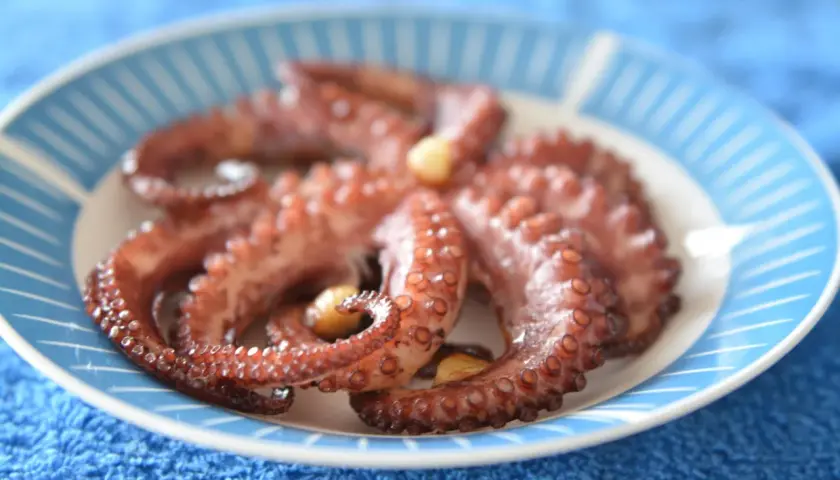 Gotowy ośmiorniczki przepis na talerzu. Delikatne macki z czosnkiem, gotowe do podania.